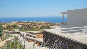 A coastal view with a white building and stone steps leading down to a garden with lavender. - NiMa Sifnos Residences (Sifnos)