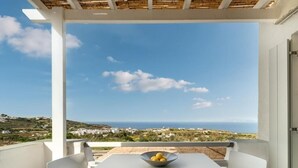 A balcony with a table and chairs, a bowl of lemons, and a view of the sea and landscape. - NiMa Sifnos Residences (Sifnos)