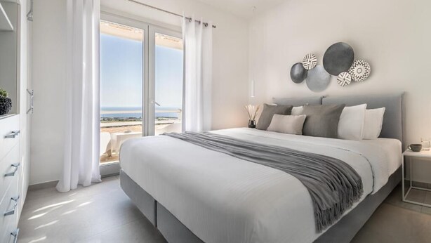 A modern bedroom with a large bed, a view of the beach, and a minimalist decor. - NiMa Sifnos Residences (Sifnos)