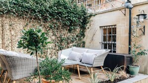 Uma área externa com mobiliário de vime e plantas em vasos.