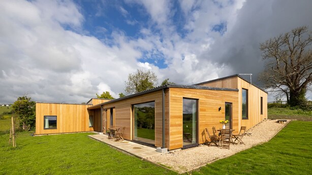 Een modern houten huis met grote ramen en een terras.