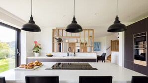 Een moderne keuken met een centraal eiland, hanglampen en uitzicht op de omgeving.