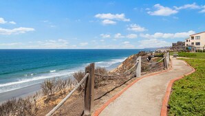 Ein Küstenweg mit Blick auf das Meer und einem Gebäude im Hintergrund.