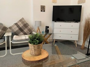 Relax in this stylish living room with a comfortable sofa, flat-screen TV, and a coffee table surrounded by lush greenery.