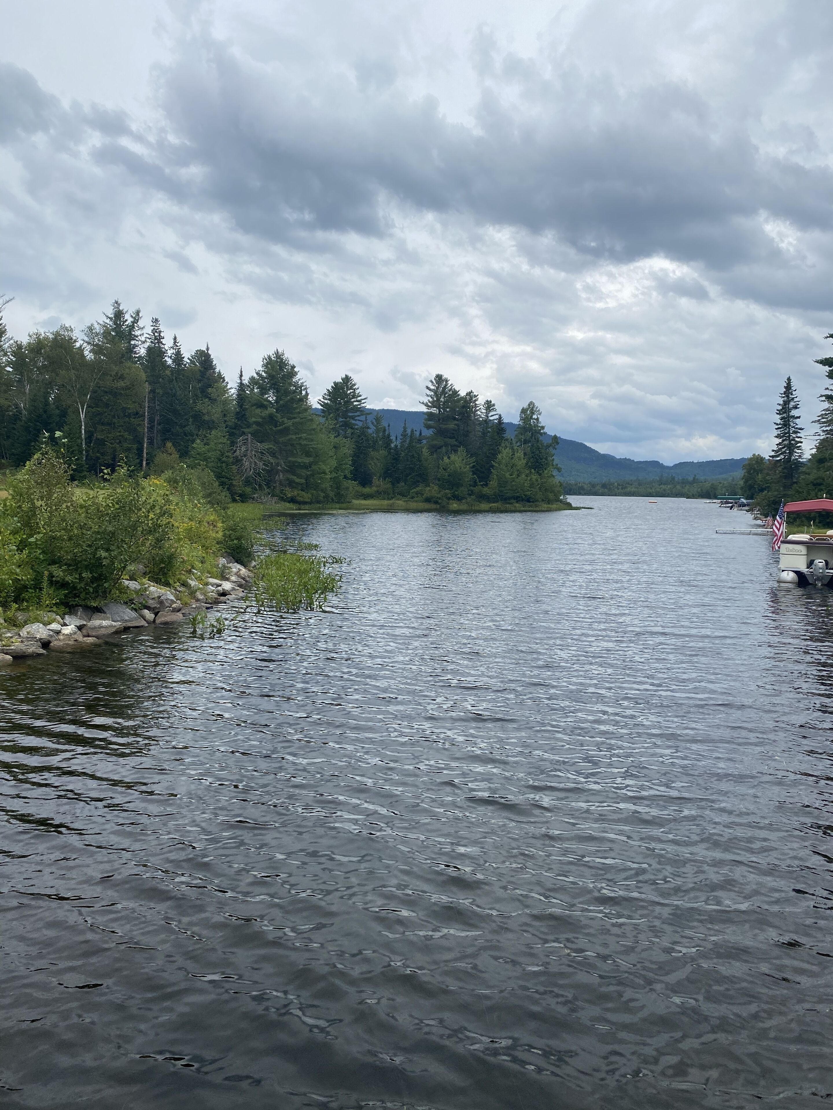 A calm river with a dock and an American flag on the right.