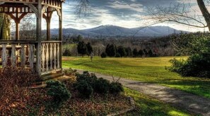 Situated in a serene grassy area, this classic gazebo offers a tranquil escape amidst rolling hills and a mountain range.