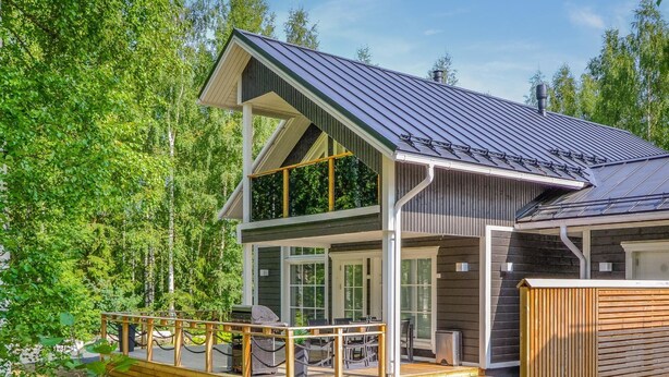 A two-story cabin with a deck, large windows, and a metal roof. - Tonttutahko 20 b by Interhome (Nilsiä)