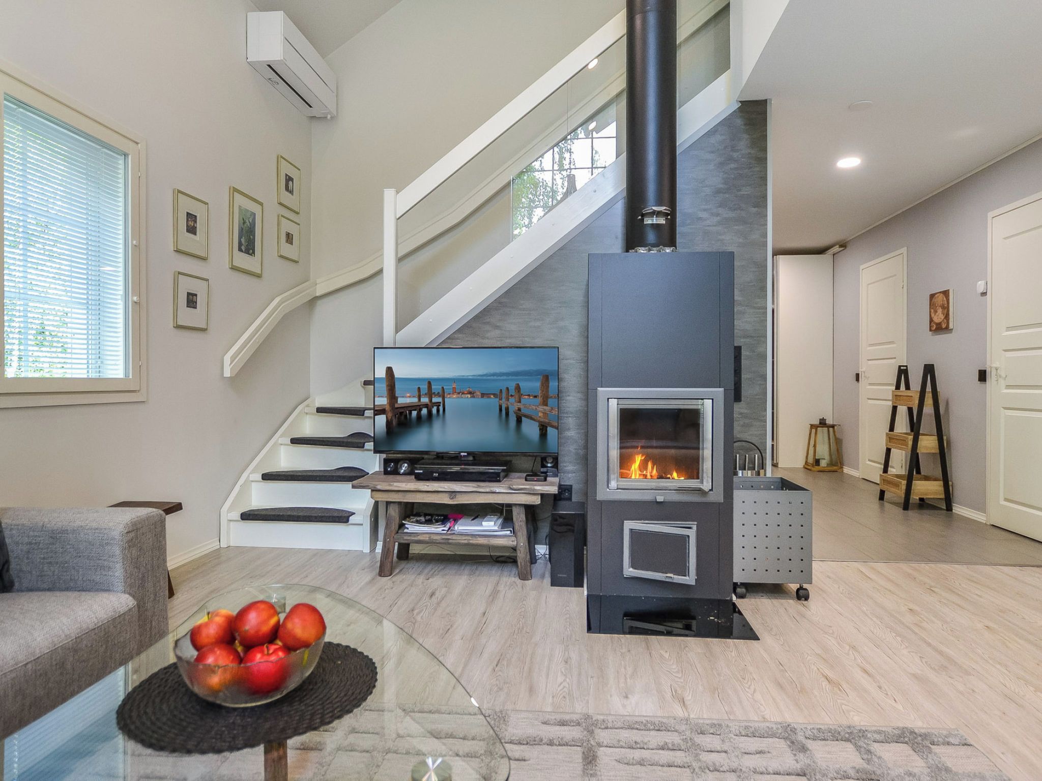 A modern living room with a fireplace, a staircase, and a TV.
