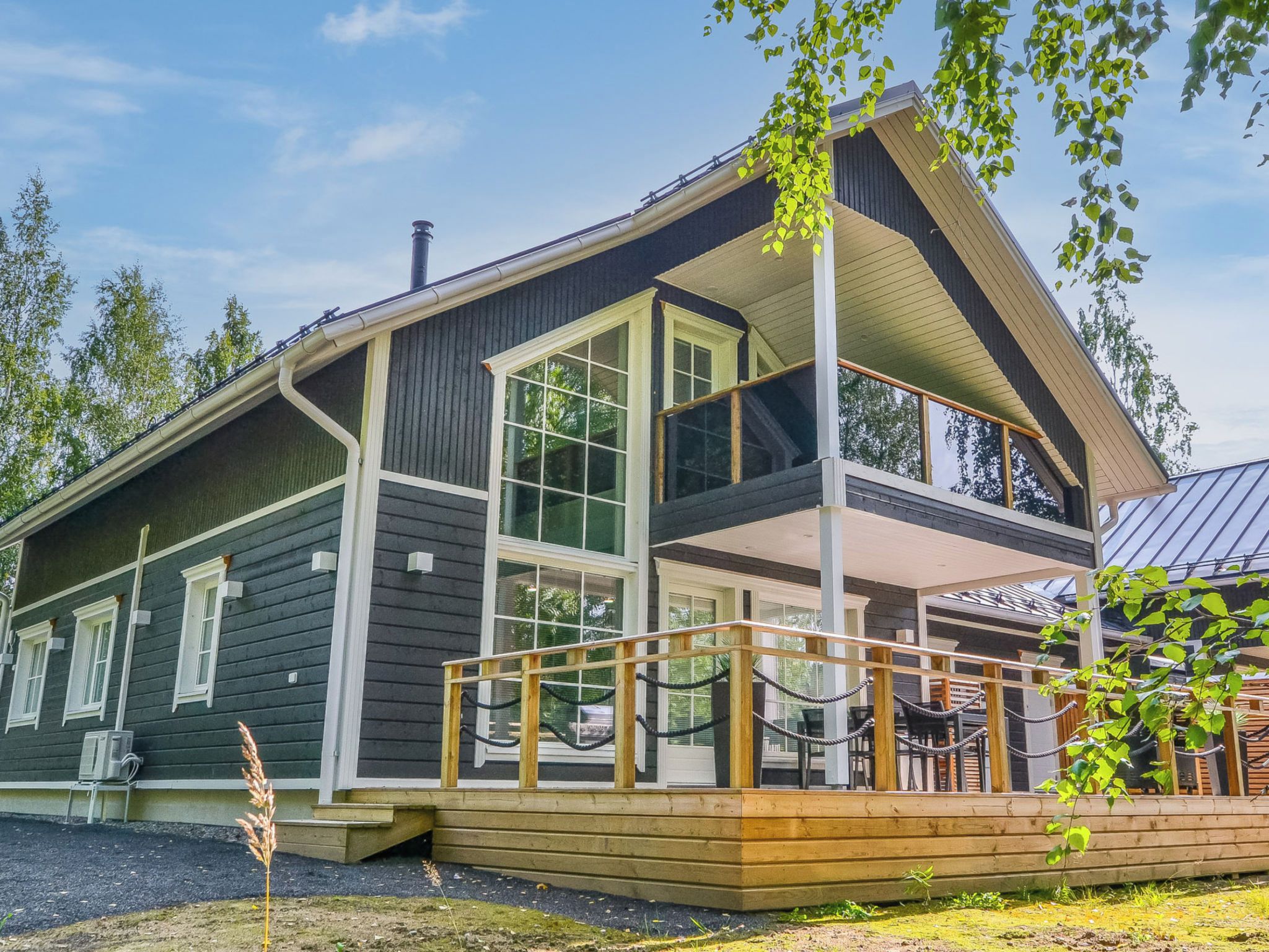 A two-story cabin with a large deck and a covered outdoor seating area.