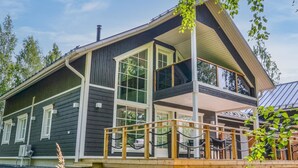A two-story cabin with a balcony, large windows, and a deck area. - Tonttutahko 20 b by Interhome (Nilsiä)