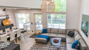 A spacious living area with a large window, a sofa, a coffee table, and a dining area with chairs and a table. - Tonttutahko 20 b by Interhome (Nilsiä)