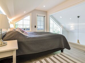 A bedroom with a bed, a nightstand, a lamp, and a window.