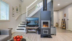 A modern living room with a fireplace, a TV, and a staircase. - Tonttutahko 20 b by Interhome (Nilsiä)
