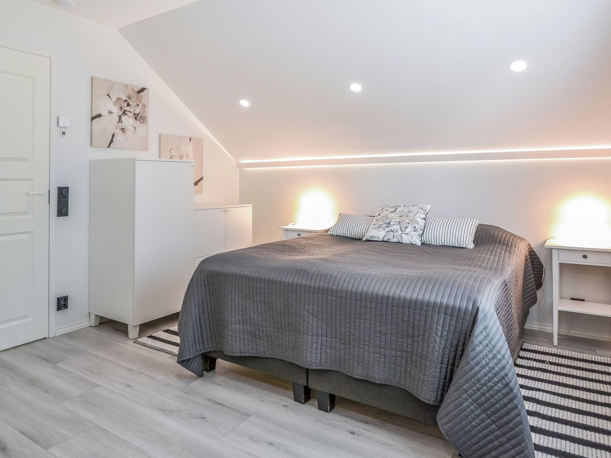 Ein modernes Schlafzimmer mit einem großen Bett, Nachttischen, einem Kleiderschrank und einer Treppe.
