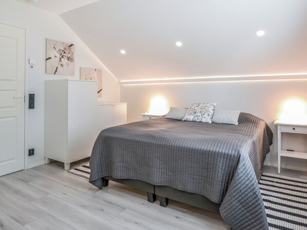 Un dormitorio moderno con una cama grande, mesitas de noche, un armario y una escalera.