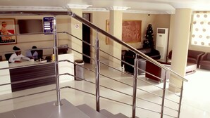 Un hall d’hôtel avec un comptoir d’accueil, un escalier doté de rampes en métal et un sapin de Noël.