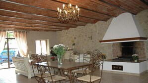 A dining area with a wooden table and chairs, a chandelier, a stone wall, and a fireplace. - Typical Provencal farmhouse (Villelaure)