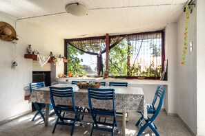 Un coin repas avec une table et des chaises, une fenêtre donnant sur un paysage verdoyant et un ventilateur de plafond.