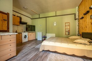 Un dormitorio con cama, lavadora, refrigerador pequeño, armarios de madera y radiador.