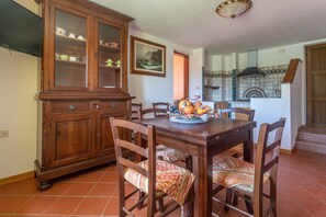 Un coin repas avec une table en bois, des chaises, un buffet et une cuisine en arrière-plan.
