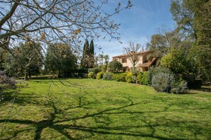 Une maison entourée d’un jardin bien entretenu, où l’on trouve différentes espèces d’arbres et d’arbustes.