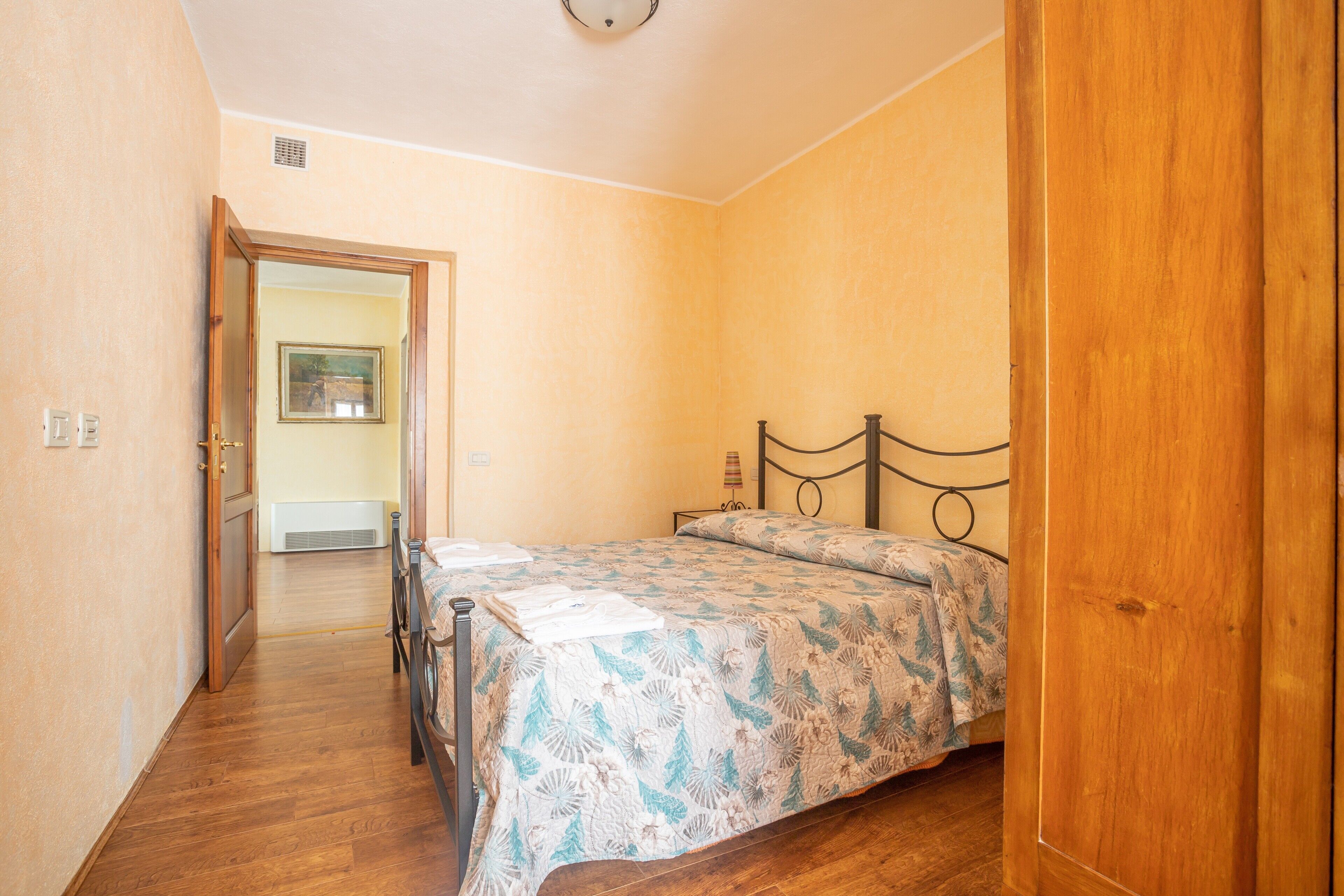 Un dormitorio con una cama de madera, una puerta que da a otra habitación y un aire acondicionado instalado en la pared.