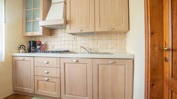 A kitchen with wooden cabinets, a tiled backsplash, a coffee maker, and a sink.