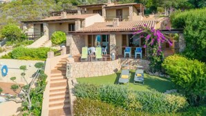 Une villa située sur une colline, dotée d’un patio aménagé avec des meubles d’extérieur et offrant une vue sur le paysage environnant.