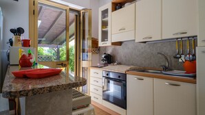 Una cocina con encimera de granito, horno empotrado y pileta con utensilios colgantes.