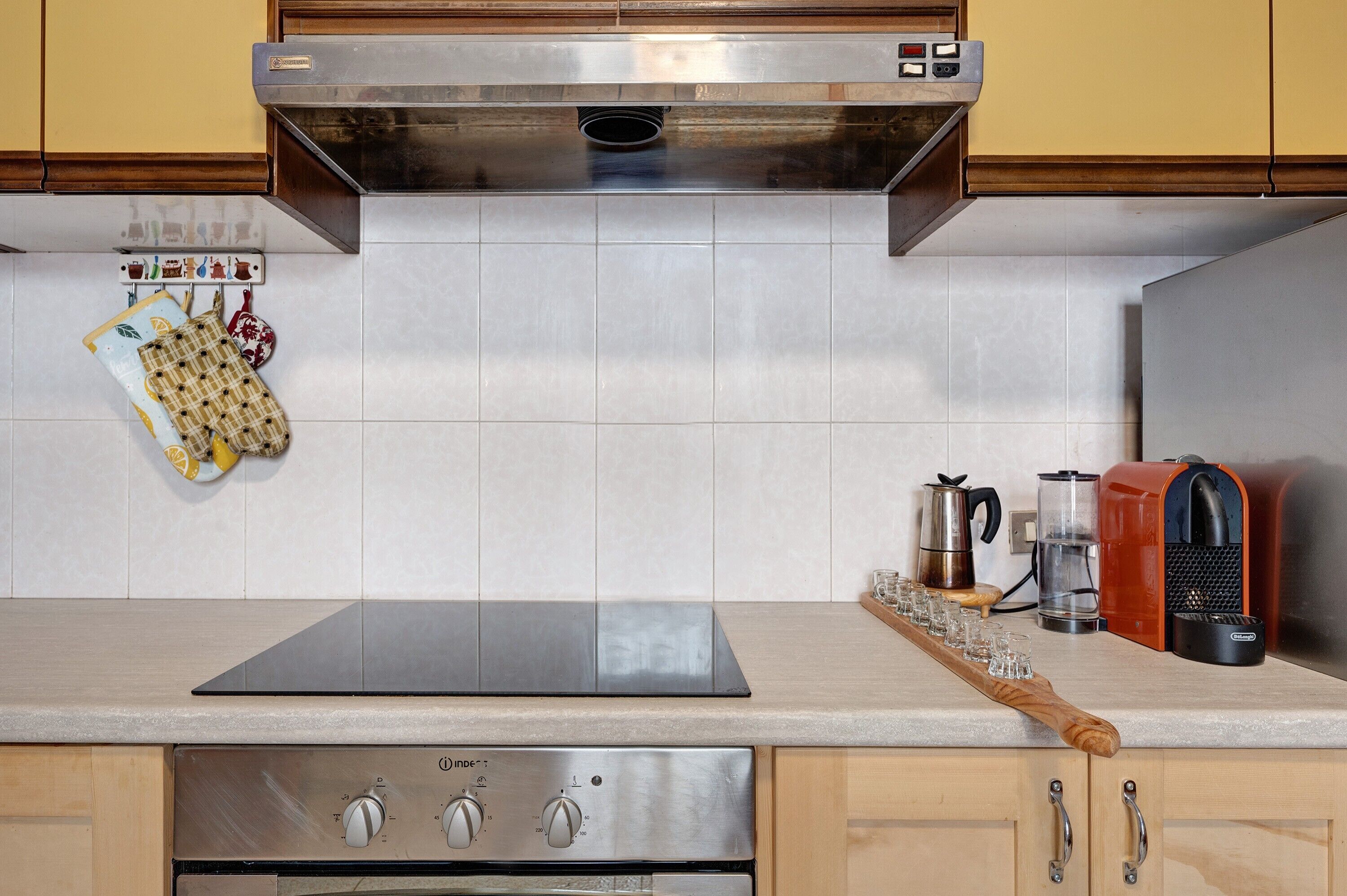 A kitchen with a stainless steel range hood, a built-in oven, and a coffee maker.