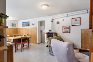 A dining area with wooden tables and chairs, a sofa, and a fireplace. - Holiday Home 'Casa della Rosina' with Mountain Views (Bresimo)