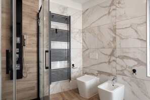 A modern bathroom with a glass shower enclosure, a built-in towel rack, a white pedestal sink, and marble walls. - Holiday Home 'Casa della Rosina' with Mountain Views (Bresimo)