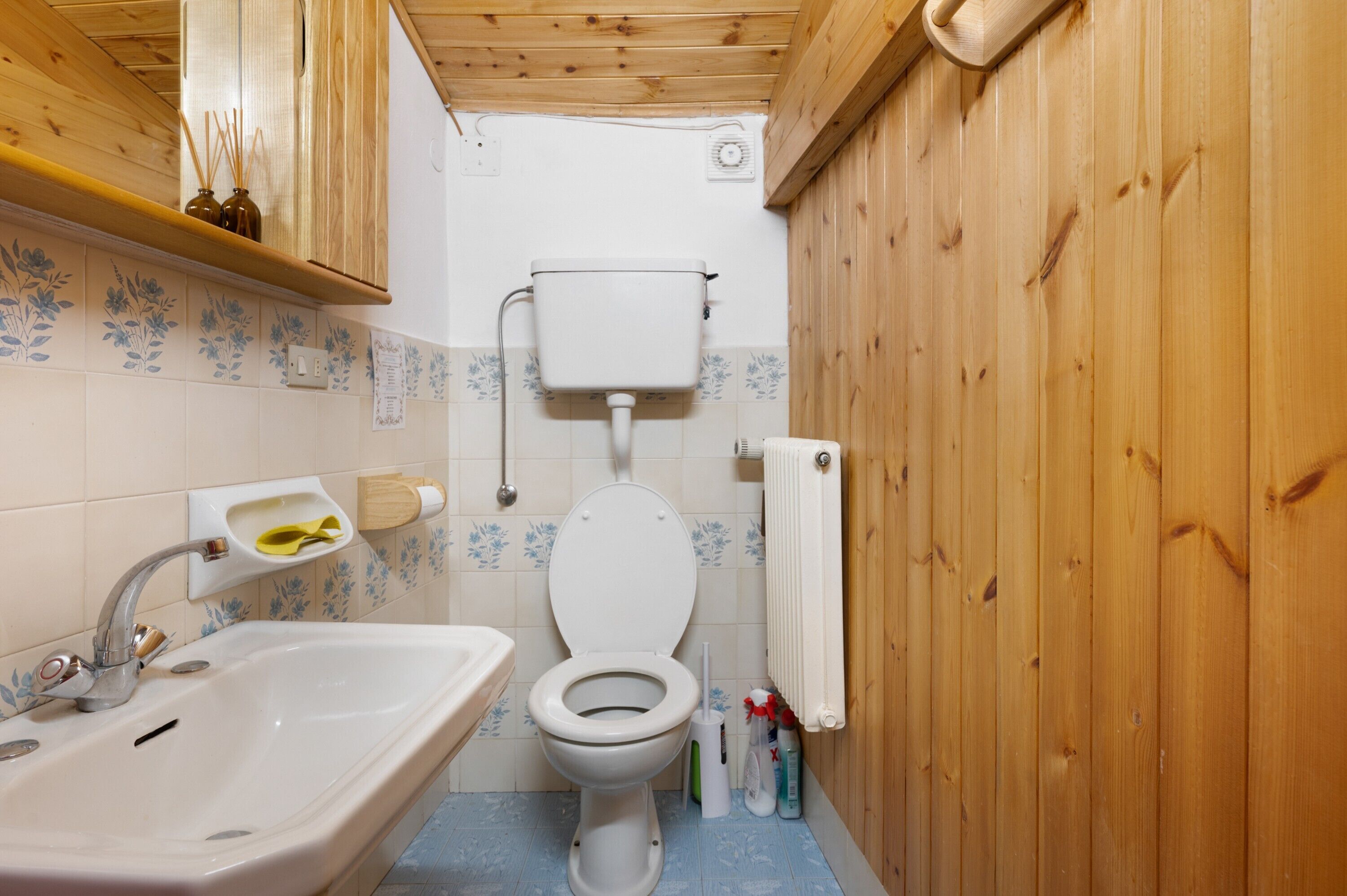 Pieni kylpyhuone, jossa on wc, pesuallas ja puuseinät.