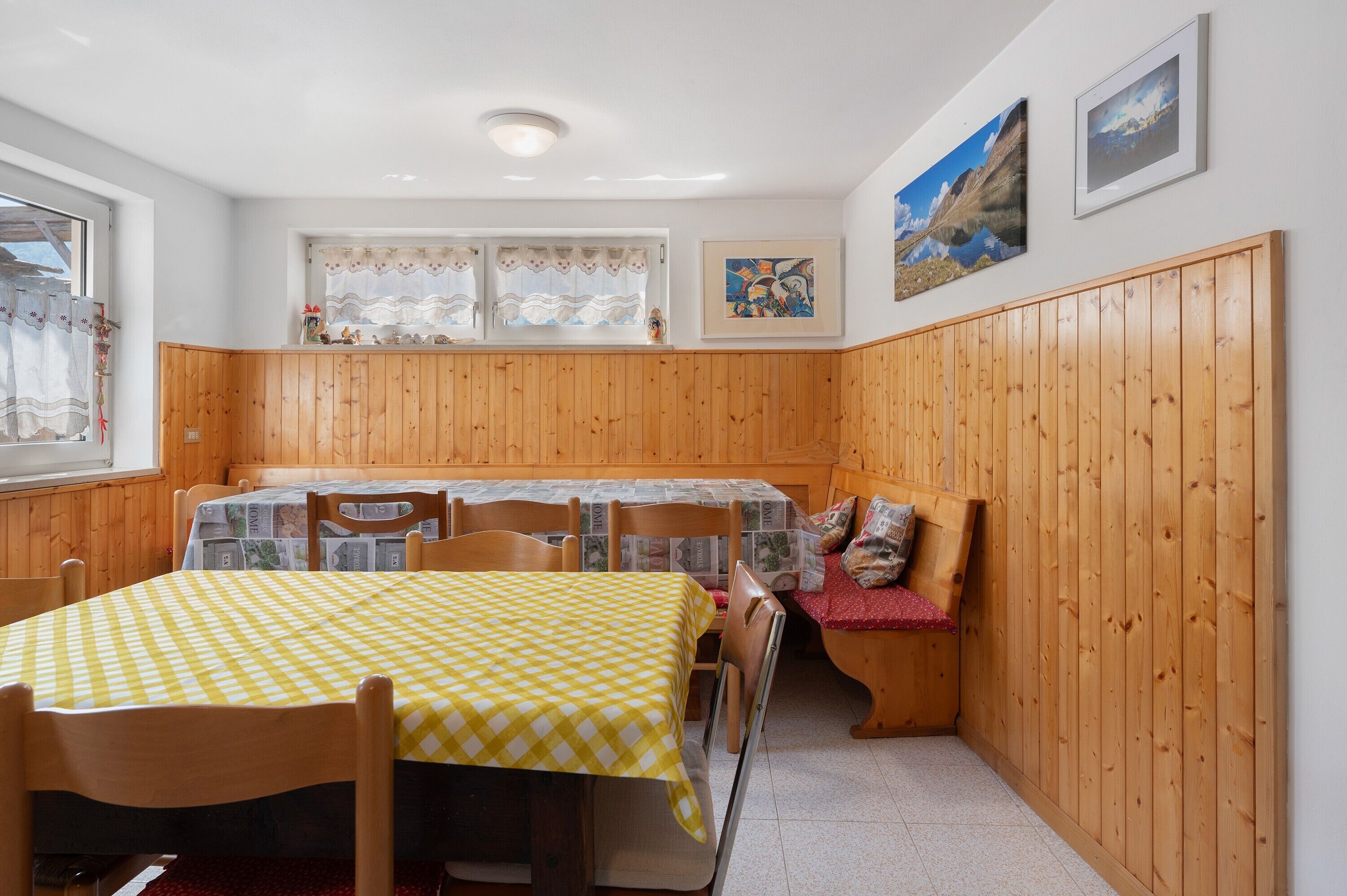 Een eetgedeelte met een tafel voor vier personen, houten lambrisering aan de wanden en twee ingelijste foto's.