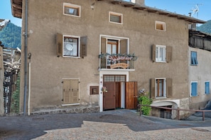A building with a wooden door, a balcony with flowers, and a sign above the door. - Holiday Home 'Casa della Rosina' with Mountain Views (Bresimo)