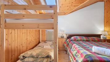 Een houten kamer met stapelbedden, een nachtkastje met een lamp, en een raam.