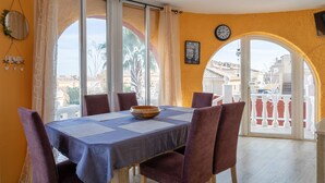 Un coin repas avec une table dressée pour quatre personnes, de grandes fenêtres et une vue sur les bâtiments environnants.