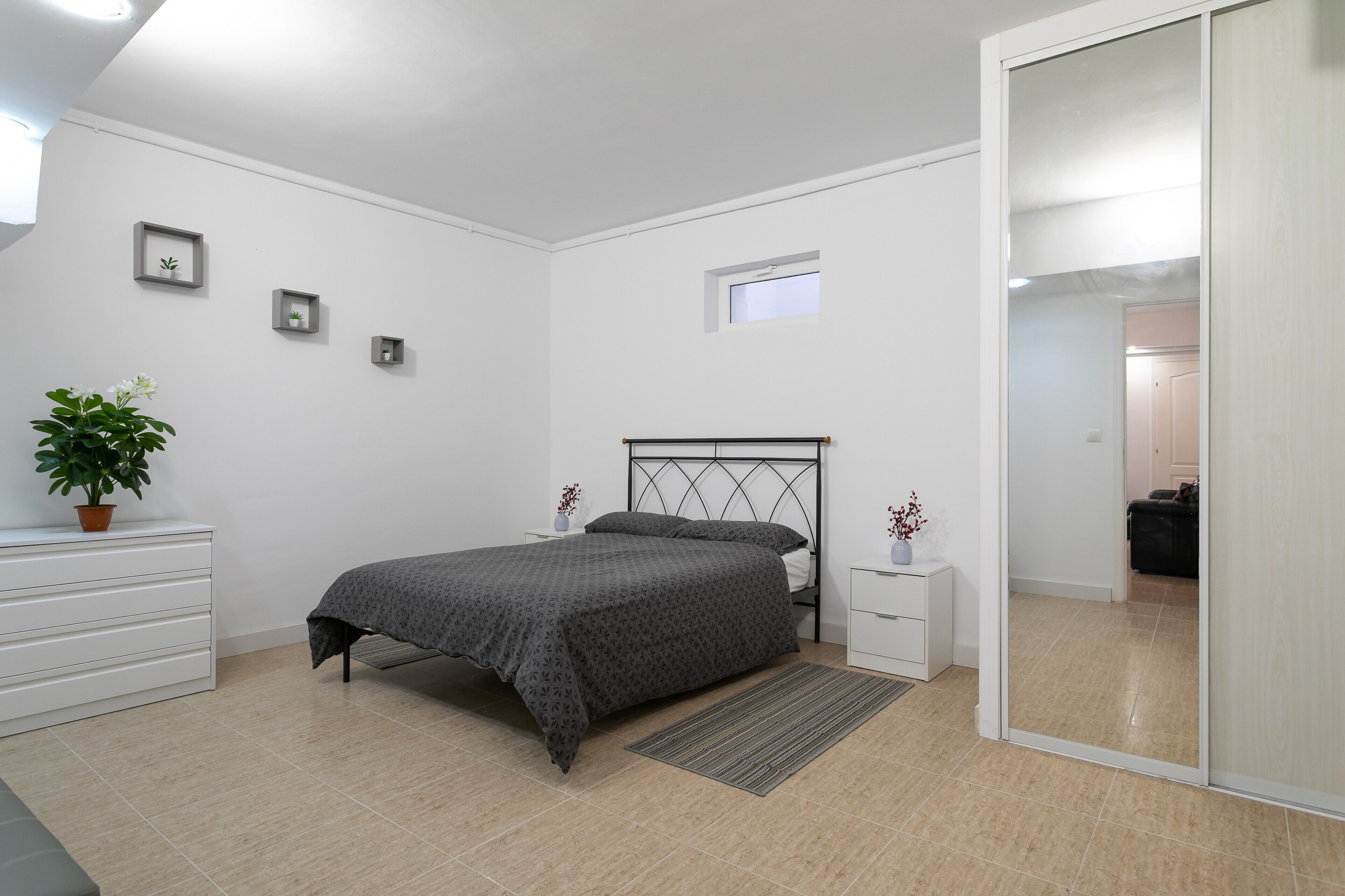Un dormitorio con cama, mesitas de noche, cómoda, ventana y puerta corredera.