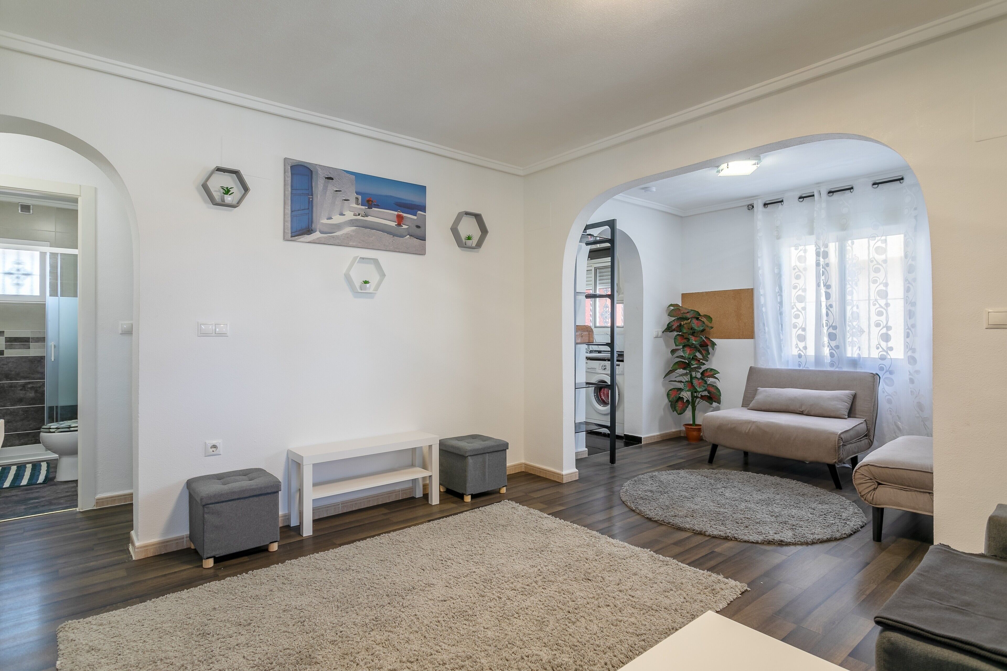 Un soggiorno moderno con un divano, una panca, un tappeto e un quadro appeso al muro.