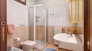 Een badkamer met toilet, bidet, douche, wastafel en een handdoekhouder.