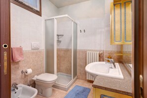 Une salle de bain comprenant des toilettes, un bidet, une douche, un lavabo et un porte-serviettes.