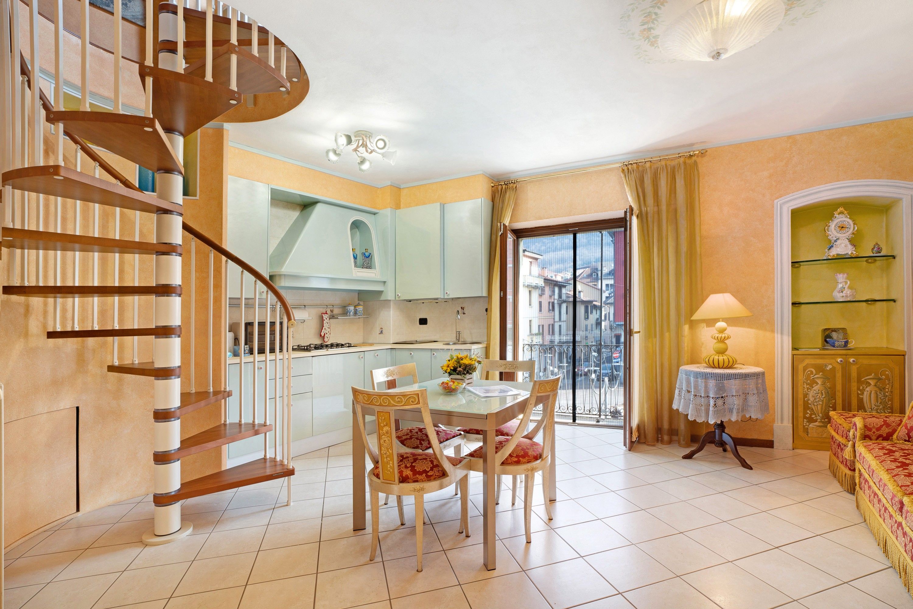 Un vaste espace de vie comprenant une table à manger, des chaises, un canapé et un escalier en colimaçon.