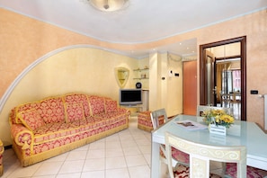 A living room with a sofa, a television, a glass table, and a chair.