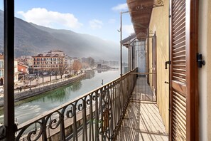 A balcony with a view of a river and buildings, a metal railing, and a door with a handle.