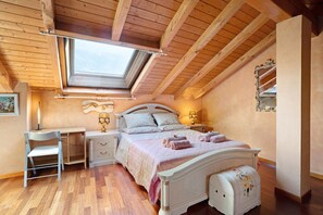 Un dormitorio con tragaluces, una cama con toallas, una mesita de noche, una silla y un aparador.