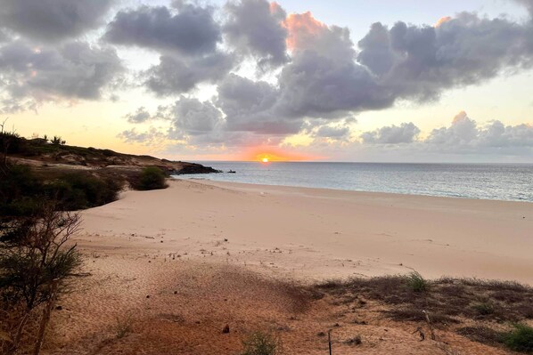 En strand med en klar himmel og solnedgang over horisonten.