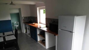A modern kitchen with a white refrigerator, wooden countertop, and a dining area with a table and chairs.