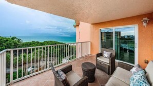 A balcony with wicker furniture, a glass door, and a view of the ocean. - Seacove in Indian Shores, Beachfront with a pool! (Indian Shores)