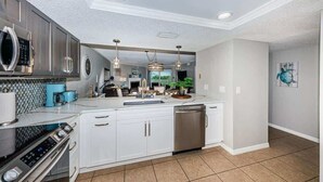 A modern kitchen with white cabinetry, stainless appliances, and pendant lighting. - Seacove in Indian Shores, Beachfront with a pool! (Indian Shores)