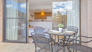 Un coin repas avec une table et des chaises, donnant sur la cuisine, et une porte-fenêtre coulissante qui mène à l’extérieur.